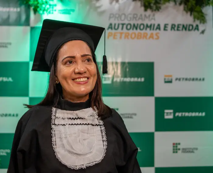 Imagem de uma estudante do programa autonomia e renda do IFES vestida de formanda e emocionada com a formatura.