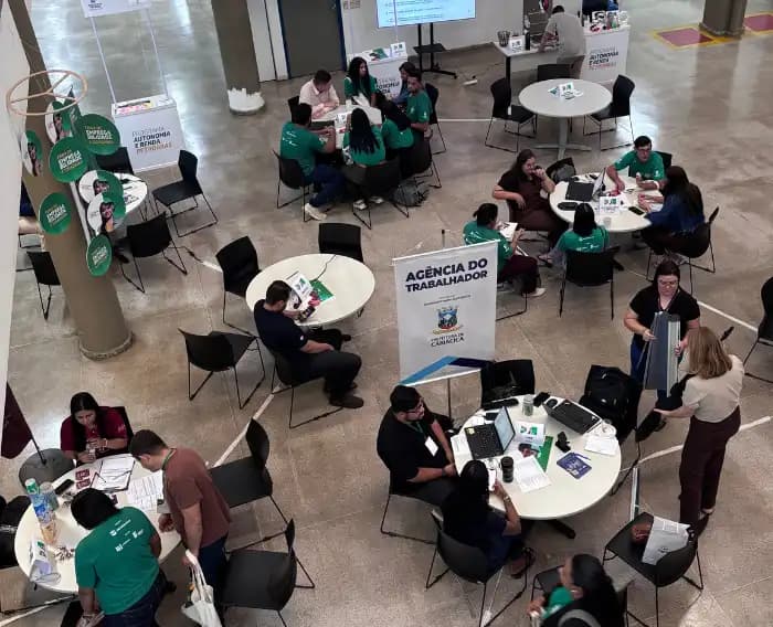 Imagem de participantes da feira distribuídos em mesas.